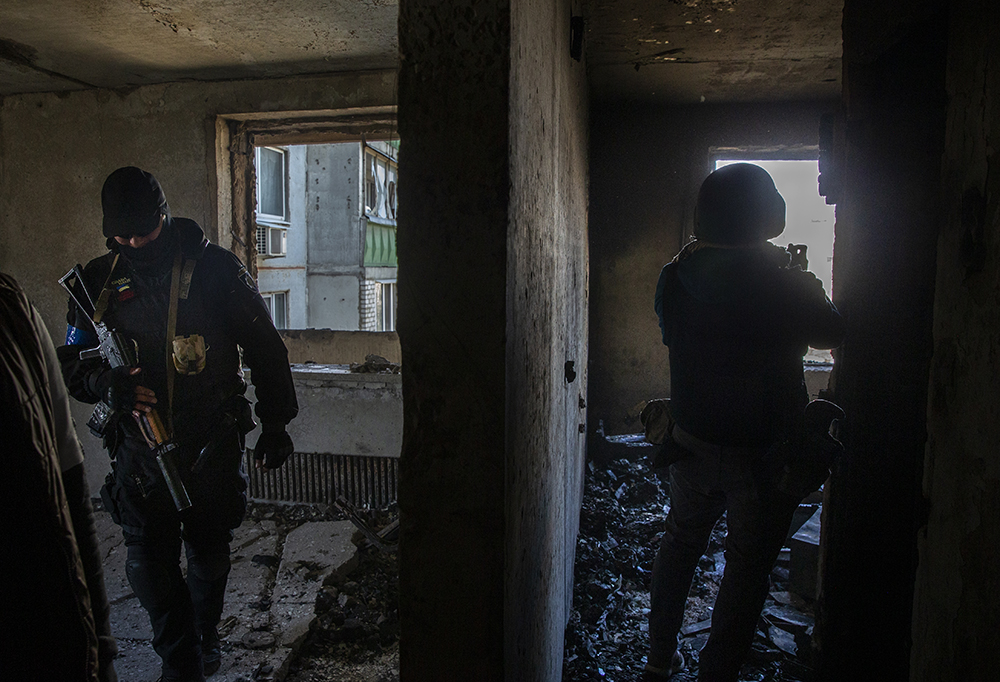 Police officer and photojournalist in destroyed building in Kharkiv, Ukraine