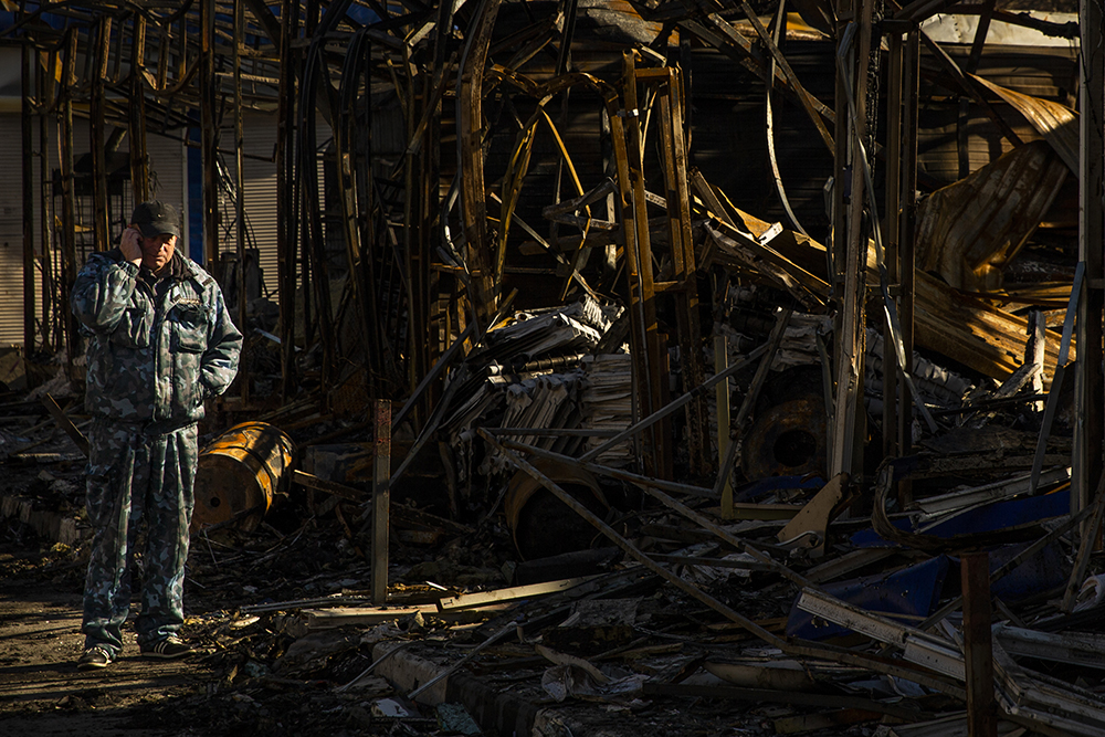 Man standing near building destroyed by Russian attack in Kharkiv, Ukraine
