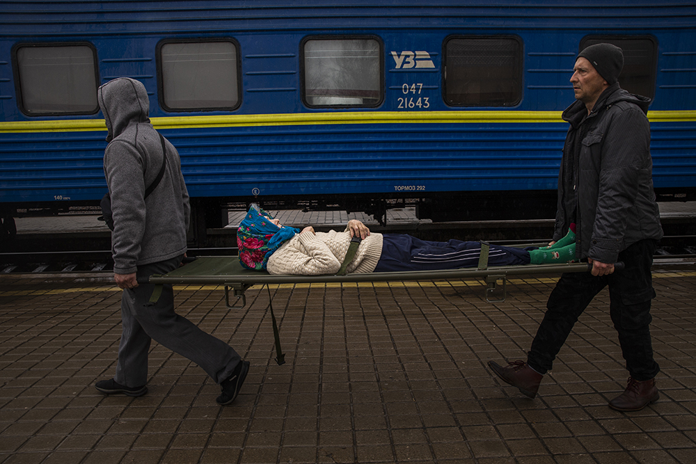 Elderly woman carried by stretcher to a train to be evacuated from Pokrovsk railway station