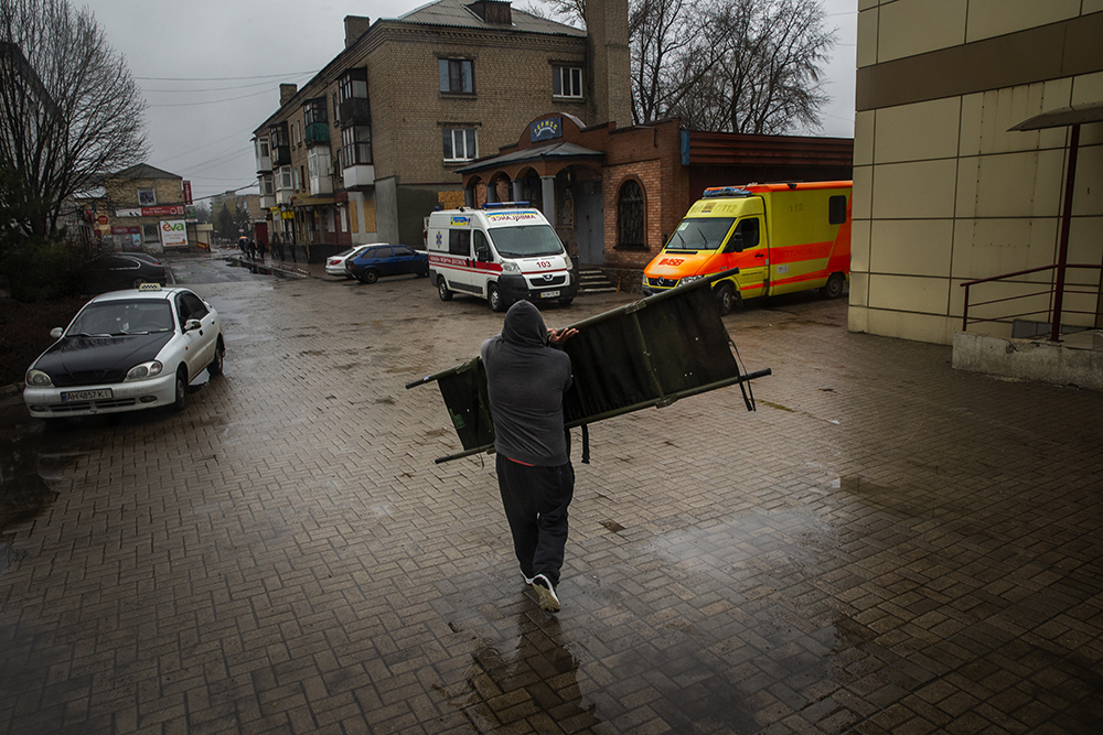 Vlad Savchenko carries a stretcher to his vehicle after helping evacuate elderly people from Donbas